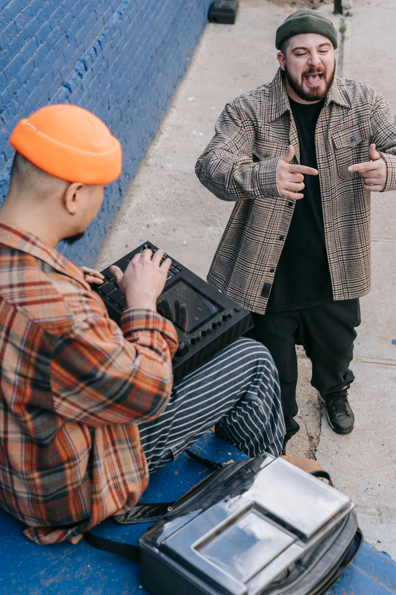 Producer on an MPC while a rapper performs in the street